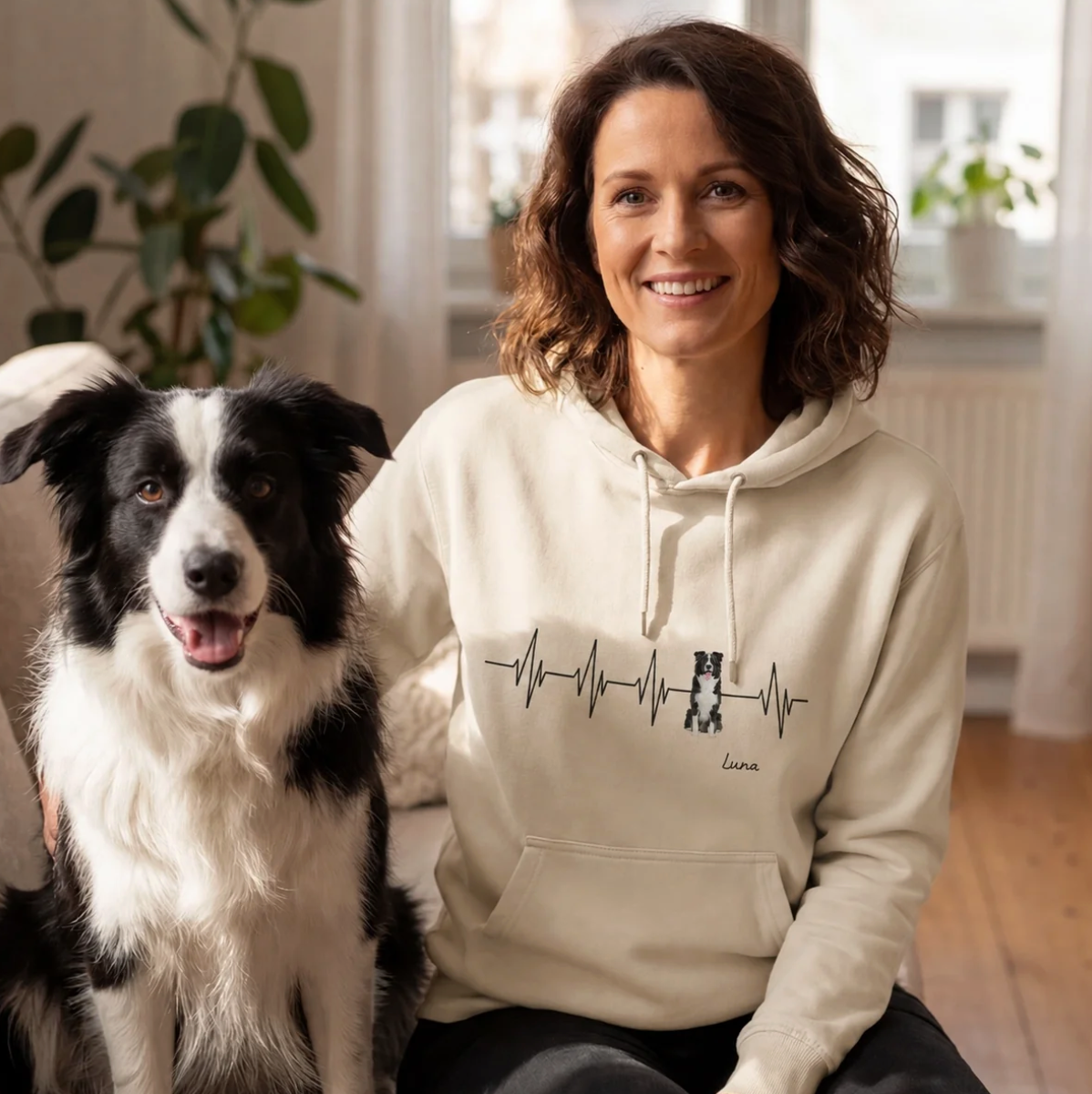 Beige Hoodie mit Herzschlag-Motiv und personalisierter Aufschrift, getragen von einer Frau neben einem Hund.