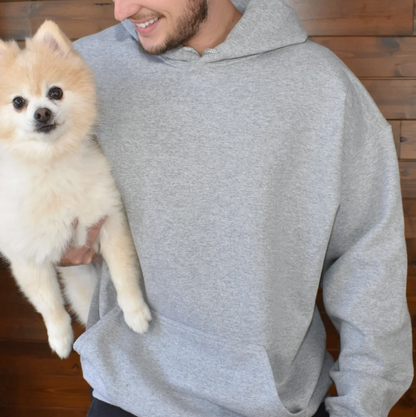 Grauer Hoodie mit großer Kapuze, gehalten von einer Person, die einen Pomeranian-Hund trägt.