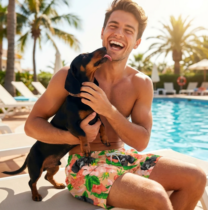 Mann mit schwarzem Hund sitzt am Pool, trägt bunte Badehose mit Blumen- und Hundemuster.