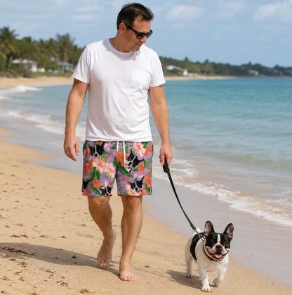Mann trägt personalisierte Badehose mit buntem Blumen- und Tiermuster und geht barfuß am Strand spazieren.