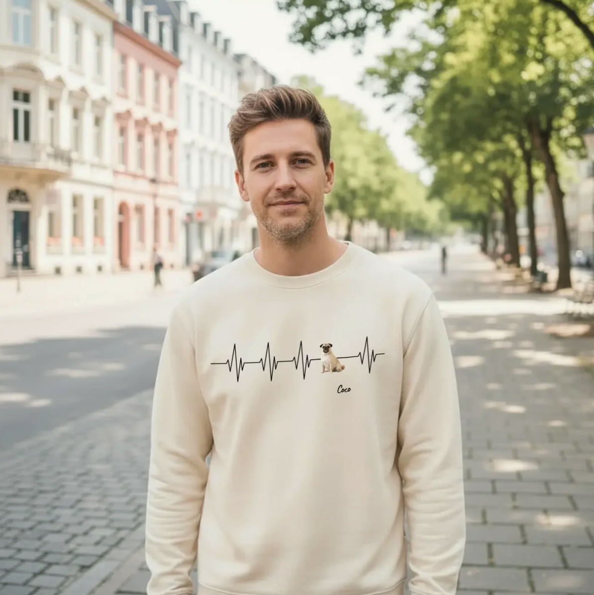 Beige Sweatshirt mit Herzschlag-Motiv und Hund, getragen von einem Mann in einer Stadtlandschaft.