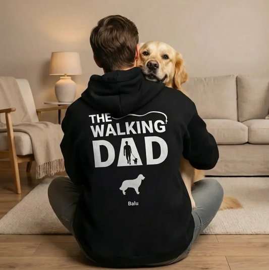 Person sitzt mit einem Hund auf dem Schoß in einem schwarzen Hoodie mit dem Aufdruck "The Walking Dad".