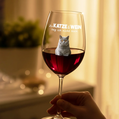 Weinglas mit Gravur und einer Katze im Glas, gefüllt mit rotem Wein.