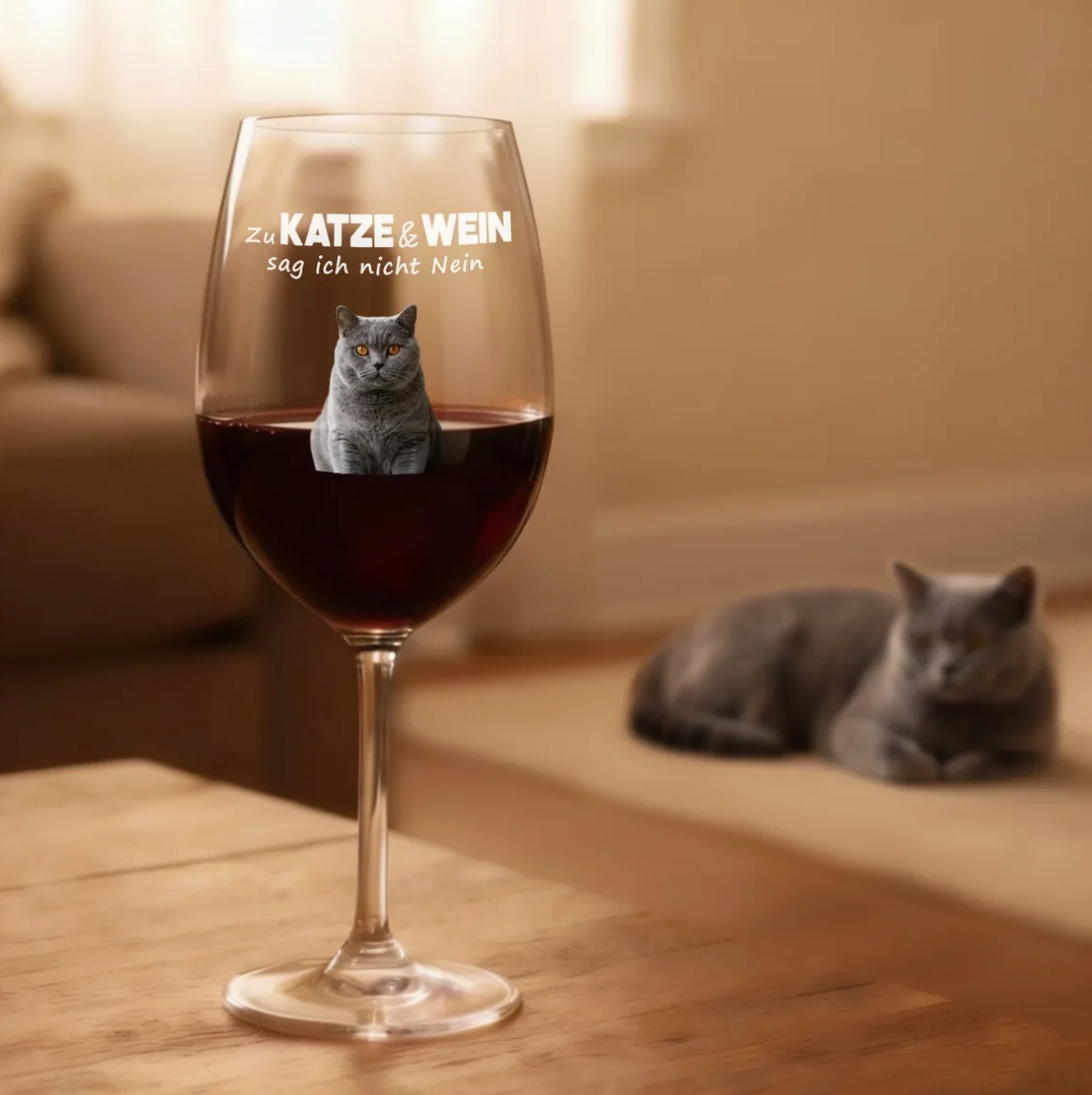 Personalisiertes Weinglas mit Aufdruck und rötlichem Wein, Katzenmotiv im Glas, Holzuntergrund.