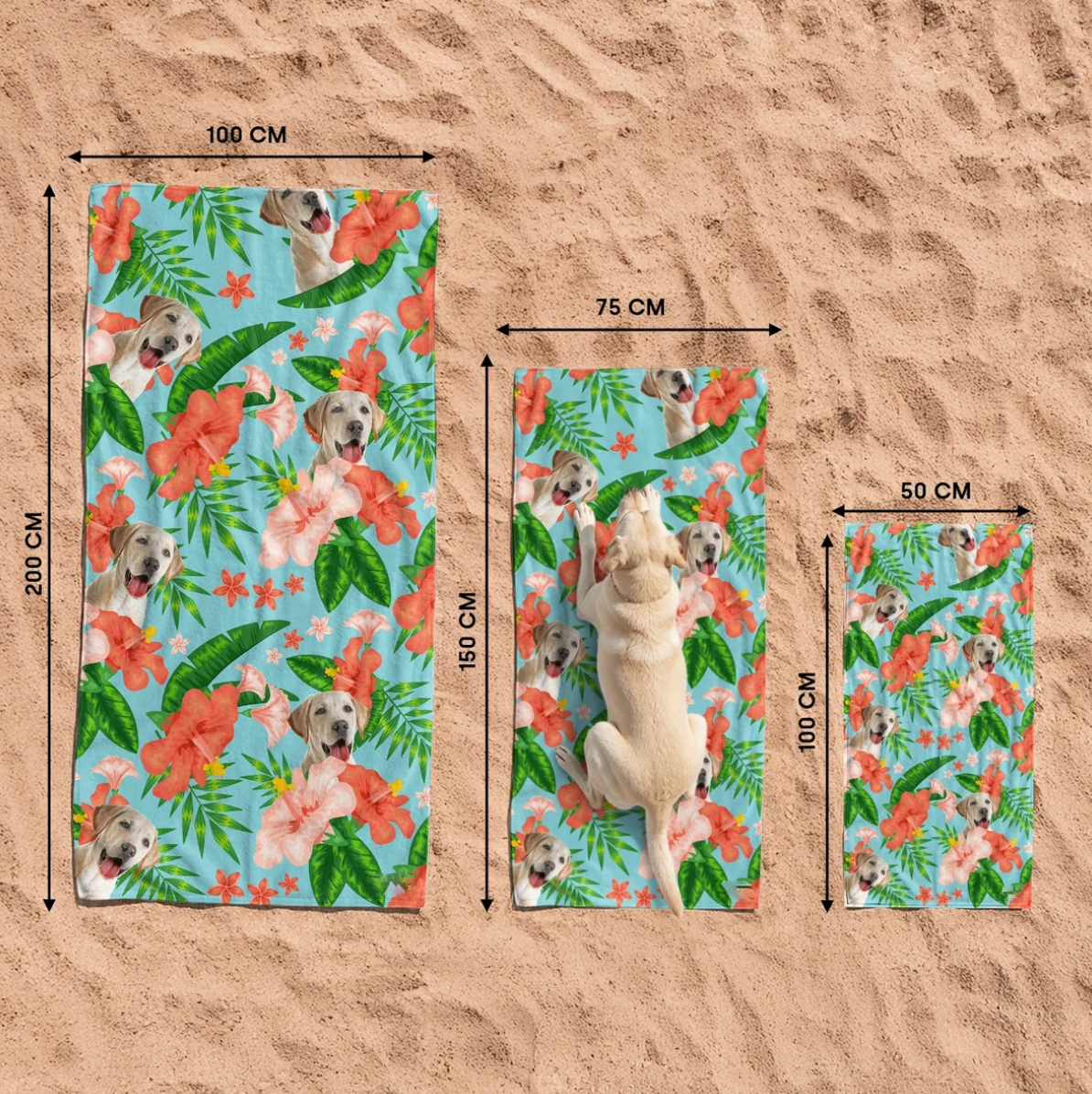 Drei personalisierte Strandtücher mit Hundemotiv und farbenfrohen Blumen auf sandigem Untergrund.