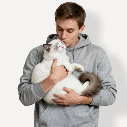 Mann im grauen Hoodie umarmt eine weiße Katze. Hintergrund in neutralem Farbton.