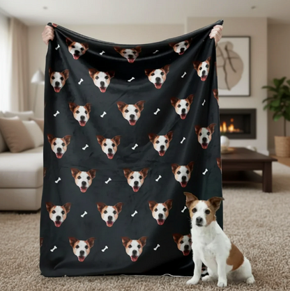 Personalisierte Decke mit Haustierköpfen auf schwarzem Hintergrund, gehalten von einer Person mit einem Hund im Vordergrund.