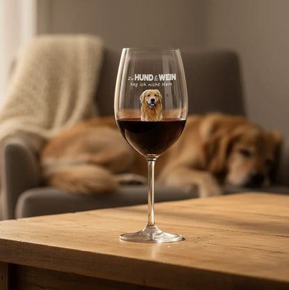 Personalisiertes Weinglas mit Hundemotiv und Schriftzug, gefüllt mit Rotwein auf einem Holztisch.