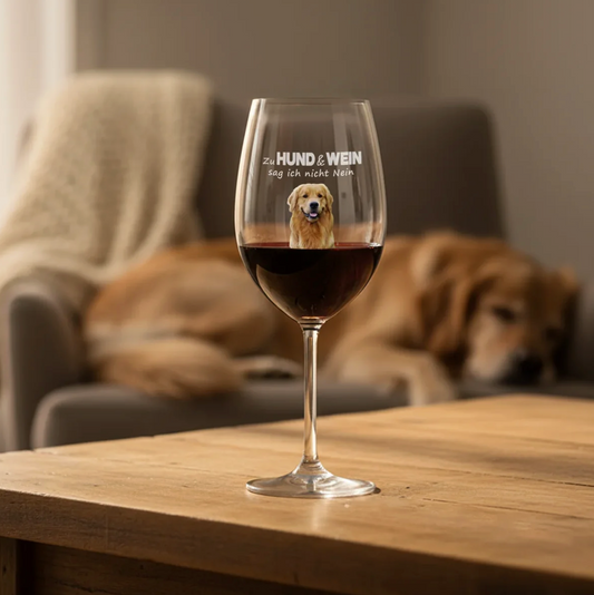 Personalisiertes Weinglas mit Hundemotiv und Schriftzug, gefüllt mit Rotwein auf einem Holztisch.