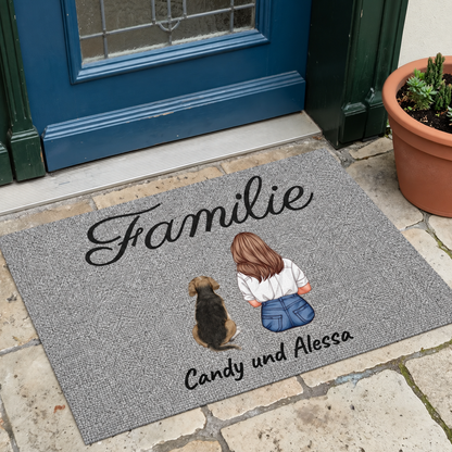 Personalisierte Fußmatte in Grau mit dem Schriftzug "Familie" und den Namen Candy und Alessa sowie einer Illustration von einer Person und einem Hund.