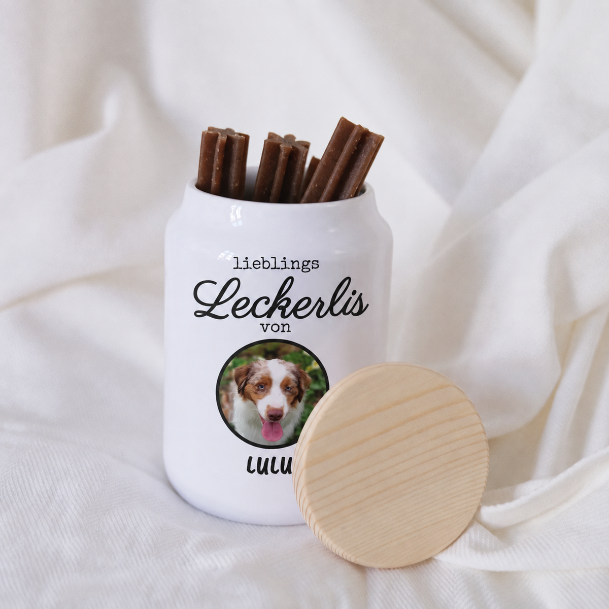Weißes Keramikglas mit Holzdeckel, gefüllt mit Hundeleckerlis, personalisierbar mit Foto und Text.