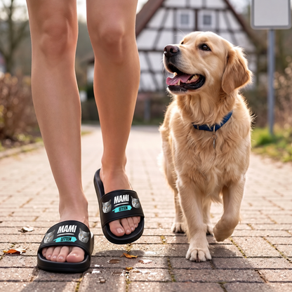 Personalisierte Badelatschen mit Aufschrift „MAMI“ und Tiermotiven, schwarz, getragen von einer Person auf einem Weg.