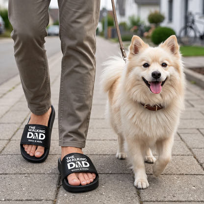 Person trägt personalisierte Badelatschen in Schwarz mit dem Aufdruck "THE WALKING DAD" und geht mit einem Hund.