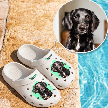 Weiße Clogs mit einem Haustierportrait eines Hundes und dem Namen "Vasco" auf grüner Hintergrundgrafik.