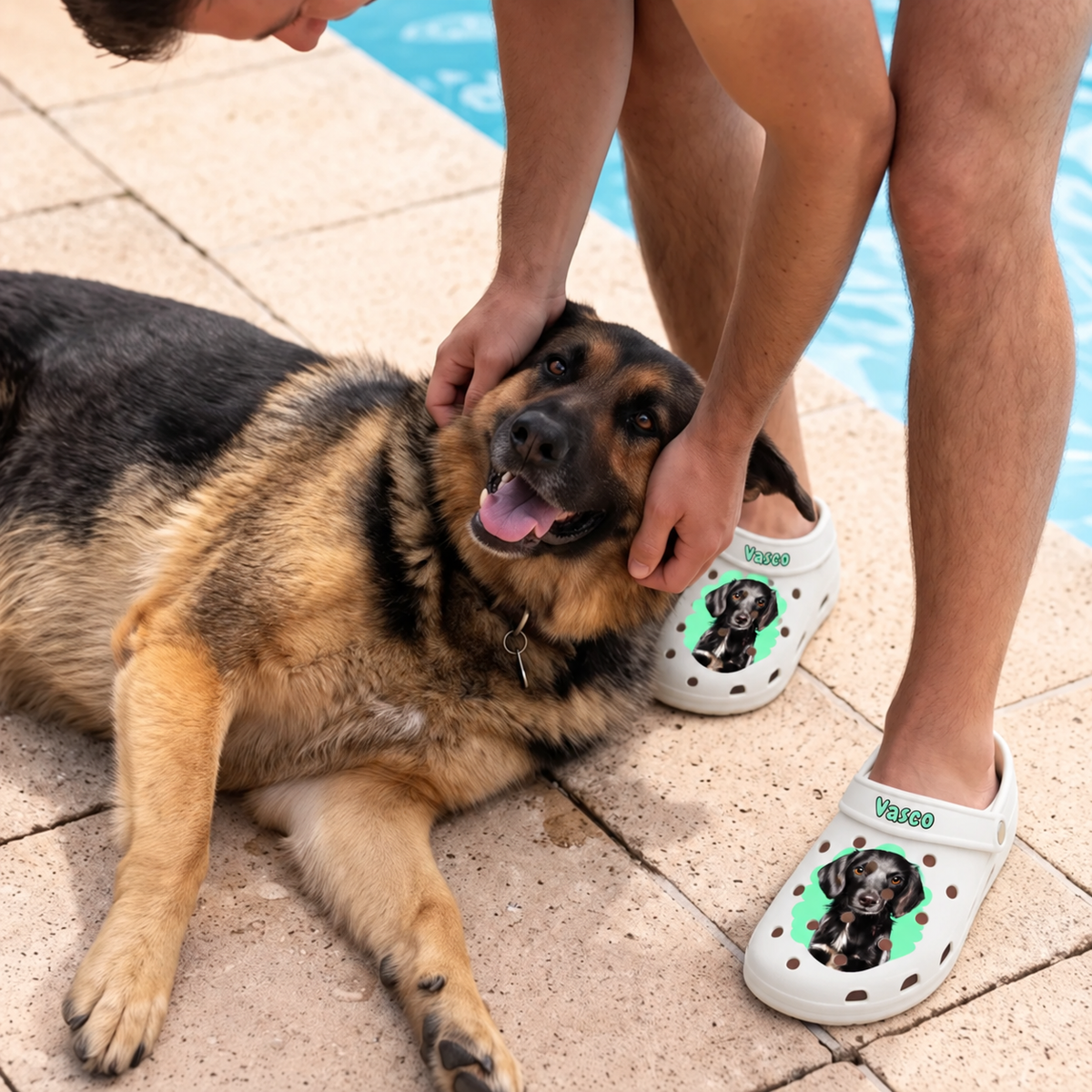 Person trägt personalisierte weiße Clogs mit Haustierportrait, sitzt neben einem Hund am Wasser.