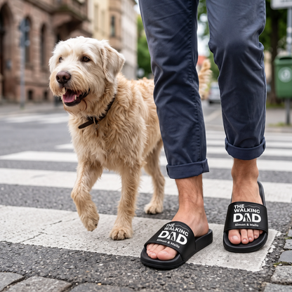 Schwarze Badelatschen mit Aufdruck "The Walking Dad" und personalisierten Namen, getragen von einer Person auf der Straße.
